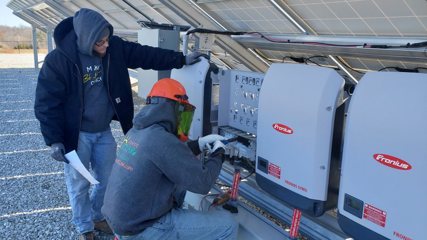 Two Dogwood staff members are working on the large solar system on a commercial rooftop.